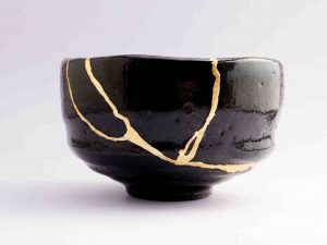 A handmade narrow bottom black bowl which has been broken and repaired using gold to fill the cracks and joins.